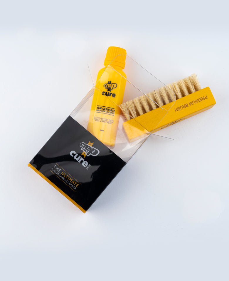 Yellow bottle and brush with 'The Ultimate' packaging on a white background